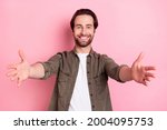Photo of impressed cute young man wear brown shirt open arms wanting hug you smiling isolated pink color background