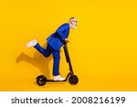 Full size profile side photo of happy excited crazy mature man look copyspace riding scooter isolated on yellow color background