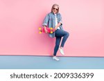 Full length photo of charming old funky woman hold hands longboard feel young isolated on pink color background