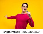Photo of nice brunet millennial guy sing wear red sweater isolated on yellow color background