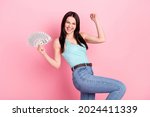 Photo of lucky millennial lady hold money hand fist wear blue top jeans isolated on pink background