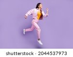 Full length profile photo of funny young brunette lady run wear jacket jeans sneakers isolated on violet background
