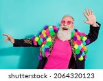 Small photo of Photo of funny excited mature guy dressed craft pom-pom jacket eyewear smiling dancing isolated turquoise color background