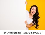 Portrait of attractive cheerful wavy-haired girl holding big board copy empty space offer isolated over bright yellow color background