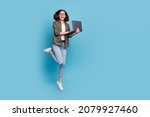 Small photo of Full length photo of excited lady computer geek it developer jump use gadget wear shirt denim jeans isolated over blue color background