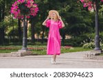 Full length body size photo woman wearing hat walking in green city park wearing long pink dress
