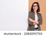 Small photo of Photo of funny lady indicate finger poster empty space wear glasses khaki shirt isolated beige color background