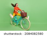 Full size profile side photo of young excited woman have fun shout ride bicycle fast isolated over green color background