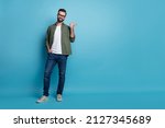 Photo of confident promoter guy indicate thumb empty space wear green shirt jeans isolated blue color background