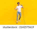 Full body photo of cute young brunet guy sing wear eyewear t-shirt jeans footwear isolated on yellow background