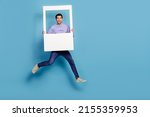 Full length body size view of attractive cheery guy jumping holding photo frame window isolated over bright blue color background