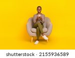 Photo of positive cute lady dressed checkered shirt sitting chair chatting modern gadget isolated yellow color background