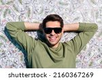 Small photo of High angle view photo of cheerful man laying usd banknotes hands head isolated on money background