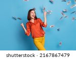 Small photo of Photo of young excited girl rejoice success luck fists hands rich triumph fly cash look empty space isolated over blue color background