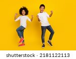 Photo of funky lucky schoolboy schoolgirl wear white shirt rising fists isolated yellow color background
