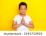 Small photo of Photo of calm pretty kid arm palms together eyes closed plead request wear white outfit isolated on yellow color background