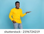Small photo of Photo of nice multinational dude hold new production on open arm wear cool yellow shirt outfit isolated blue color background