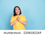 Photo portrait of cute young girl korean hold hands together look copyspace dressed stylish yellow look isolated on blue color background