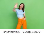 Small photo of Photo of cheerful nice person toothy smile arm palm waving hi give high five isolated on green color background