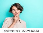 Small photo of Closeup portrait photo of charming bob brown hair girlish lady manager touch chin minded look interested empty space isolated on cyan color background