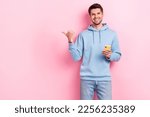Small photo of Photo of cool sweet man wear blue hoodie writing sms modern device pointing thumb empty space isolated pink color background