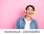 Photo of youngster relaxed girl wear denim stylish jacket looking mockup itunes enjoy her new bluetooth headphones isolated on pink color background