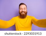 Selfie portrait of young blogger guy red hair beard hold camera recording his new video white teeth isolated on violet color background