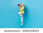 Full size photo of crazy excited girl hold loudspeaker talk empty space jumping isolated on blue color background