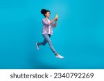 Full length photo of sweet charming girl dressed checkered shirt jumping texting modern gadget empty space isolated blue color background