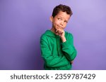 Small photo of Photo of suspicious unsure small boy wear green sweatshirt arm chin looking empty space isolated violet color background