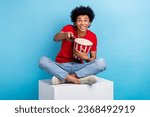 Full body cadre of crazy young man spend his holidays at home watch tv use remote control eat popcorn isolated on blue color background