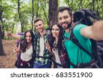 Close up of four cheerful  friends in the spring nice wood, embracing, posing for a selfie shot, that handsome brunet is taking