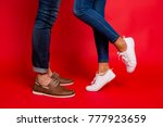 Closeup photo of woman and man legs in jeans, pants and shoes, girl with raised leg, stylish couple kissing during date, isolated over red background, he vs she