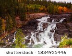 Early fall colours provide contrast to the stark rock framing Cameron falls along the Ingraham Trail in Canada