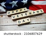 Happy Veterans Day alphabet letter and American flag on wooden background