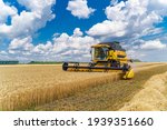 Great combine harvester working at the field. Agricultural machine on the blue sky.