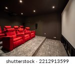 Small photo of Saint-Tropez, France - June 30th 2022 : nice little private movie theater with the black walls, gray floor, big screen on the right, comfy red seats on the left