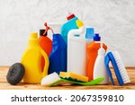 Household cleaning detergents on wooden table against gray background