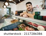 Small photo of Portrait of confident young salesman standing in butcher's shop