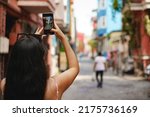 Young female tourist is exploring new city making photo on smartphone