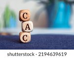 Small photo of Tower made of cubes and dice with acronym CAC customer acquisition cost on wooden background