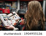 A beautiful woman in a book store holds an open comic book in the ruffs (the book is blurred).