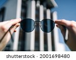 Female hands hold sunglasses (focus on them) while traveling, joy.