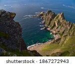 Aerial view of the rough coast of the Norwegian Sea in the north of Andøya island, Vesterålen, Norway with beautiful turquoise colored rock beach, mountains and rugged cliffs on sunny summer day.