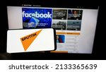 Small photo of Stuttgart, Germany - 03-01-2022: Person holding cellphone with logo of Russian state media company Sputnik on screen in front of webpage. Focus on phone display. Unmodified photo.