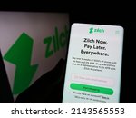 Small photo of Stuttgart, Germany - 03-30-2022: Person holding cellphone with website of fintech Zilch Technology Limited (PayZilch) on screen in front of logo. Focus on center of phone display. Unmodified photo.