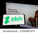 Small photo of Stuttgart, Germany - 03-30-2022: Person holding cellphone with logo of fintech Zilch Technology Limited (PayZilch) on screen in front of business webpage. Focus on phone display. Unmodified photo.