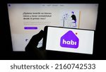 Small photo of Stuttgart, Germany - 05-20-2022: Person holding smartphone with logo of Colombian company INVERSIONES MCN S.A.S (Habi) on screen in front of website. Focus on phone display. Unmodified photo.