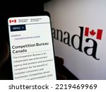 Small photo of Stuttgart, Germany - 10-14-2022: Person holding smartphone with website of Canadian regulator Competition Bureau on screen in front of logo. Focus on center of phone display. Unmodified photo.