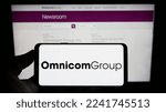 Small photo of Stuttgart, Germany - 12-10-2022: Person holding cellphone with logo of US media company Omnicom Group Inc. on screen in front of business webpage. Focus on phone display. Unmodified photo.